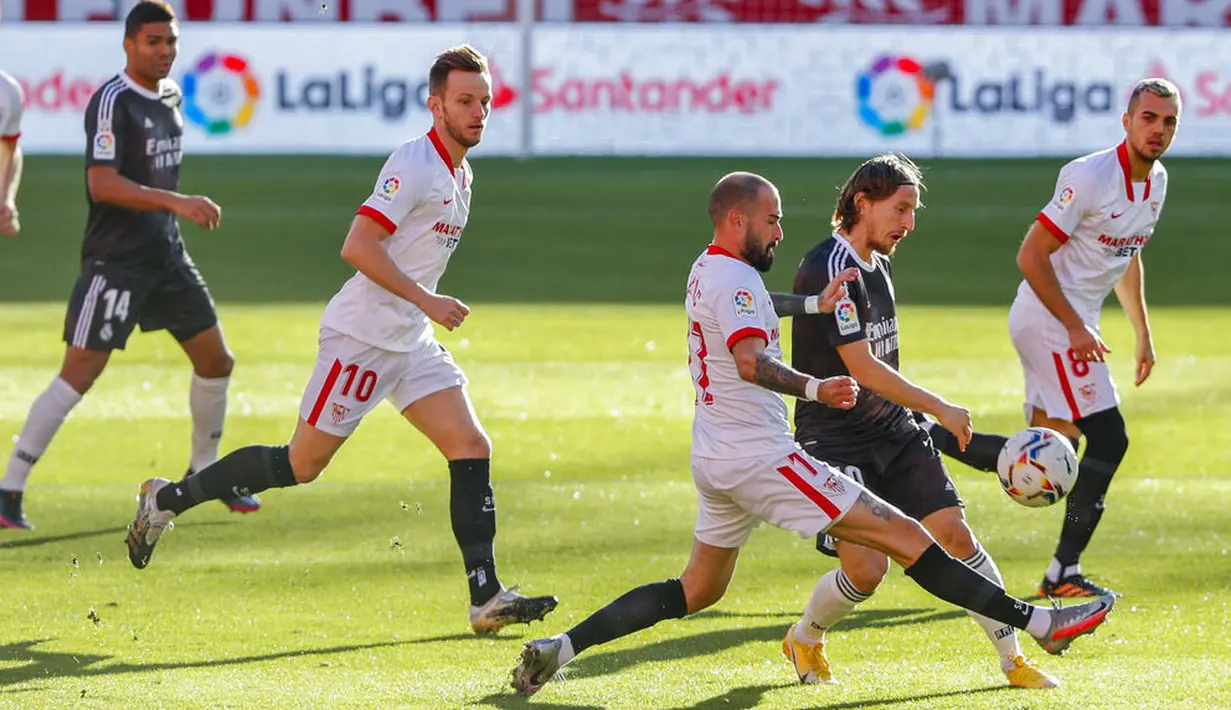 Gelandang Real Madrid, Luka Modric, berebut bola dengan pemain Sevilla, Aleix Vidal, pada laga Liga Spanyol di Stadion Ramon Sanchez Pizjuan, Minggu (6/12/2020). Real Madrid menang dengan skor 1-0. (AP/Angel Fernandez)