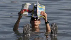 Seorang wisatawan wanita berendam sambil membaca majalah di Danau Tus, Khakassia, barat daya dari kota Siberia Krasnoyarsk, Rusia (18/7/2015). Selama musim panas, warga Rusia dari berbagai daerah melakukan perjalanan ke danau Tus. (REUTERS/Ilya Naymushin)