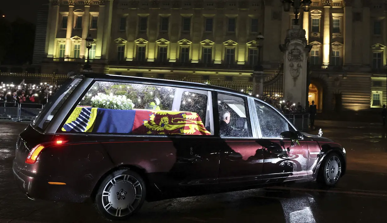 Mobil jenazah  yang membawa peti mati Ratu Elizabeth II tiba di Istana Buckingham, London, Selasa (13/9/2022). Peti mati Ratu Elizabeth II kembali ke Istana Buckingham pada Selasa malam, melewati London yang gerimis saat kerumunan orang memenuhi rute untuk melihat sekilas mobil jenazah dan mengucapkan selamat tinggal padanya. (Paul Childs/Pool Photo via AP)
