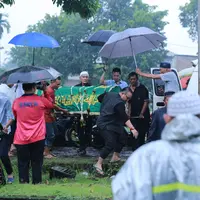 Jenazah aktor senior Deddy Sutomo saat diturunkan dari mobil ambulan. Siang itu, disekitar Tempat Pemakaman Umum Tanah Kusir, Jakarta Selatan sedang di guyur hujan. (Adrian Putra/Bintang.com)