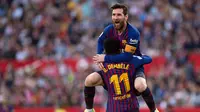 Penyerang Barcelona Lionel Messi memeluk rekan setimnya Ousmane Dembele usai mencetak gol ke gawang Sevilla pada laga La Liga di Stadion Ramon Sanchez Pizjuan, Sevilla, Sabtu (23/2). Barcelona menang 4-2. (JORGE GUERRERO/AFP)