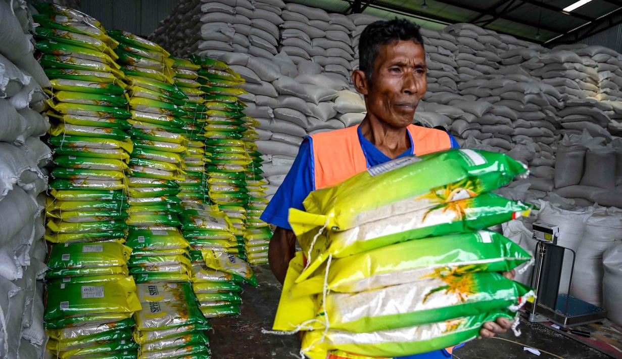 Seorang pekerja membawa karung-karung beras di gudang Badan Urusan Logistik (Bulog) di Lambaro, Provinsi Aceh pada 29 Desember 2025. Badan Urusan Logistik (Bulog) memastikan ketersediaan beras di Pulau Sumatera dalam kondisi aman dan mencukupi, khususnya untuk memenuhi kebutuhan masyarakat yang terdampak bencana banjir dan longsor di sejumlah wilayah. (CHAIDEER MAHYUDDIN/AFP)