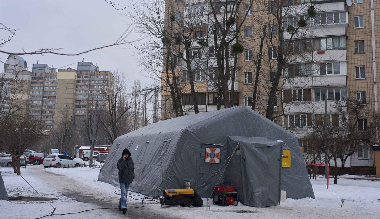 Serangan Rusia pun disebut-sebut melumpuhkan jaringan listrik untuk ratusan ribu rumah tangga di Kiev. Tampak dalam foto, seorang pria melewati salah satu tenda darurat tempat orang-orang dapat menghangatkan diri setelah serangan udara rutin Rusia terhadap fasilitas energi negara itu di tengah musim dingin, Kyiv, Ukraina, Selasa 13 Januari 2026. (AP Photo/Efrem Lukatsky)
