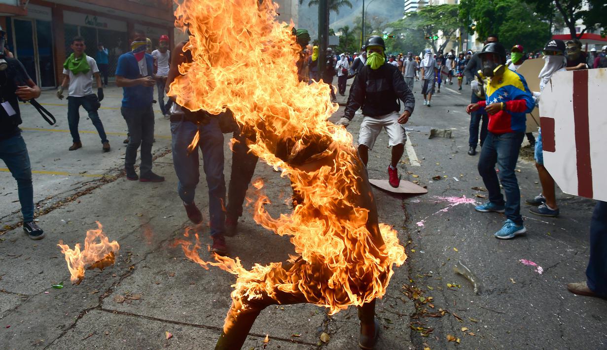 Sejumlah demosntran bereaksi saat rekannya terbakar pada unjuk rasa yang diwarnai bentrokan menentang Presiden Venezuela, Nicolas Maduro di Caracas, Rabu (3/5). Pria itu tersulut api dari ledakan tangki sepeda motor milik polisi. (RONALDO SCHEMIDT / AFP)