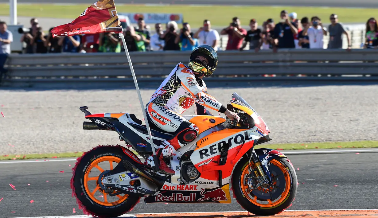 Pembalap Spanyol Repsol Honda, Marc Marquez membawa bendera di atas motor setelah memenangkan balapan seri ke 18 MotoGP Grand Prix Valencia di Sirkuit Ricardo Tormo, Valencia (12/11). Marc Marquez finis di urutan ketiga. (AFP PHOTO / Jose Jordan)