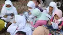 Anak-anak membaca Al-Quran sambil menunggu waktu berbuka puasa di halaman Masjid Raya Jakarta Islamic Center, Jakarta Utara, Senin (18/4/2022). Acara ngabuburit sambil khataman Al-Quran ini merupakan rangkaian acara menyambut 17 Ramadhan atau malam Nuzulul Quran. (Liputan6.com/Herman Zakharia)