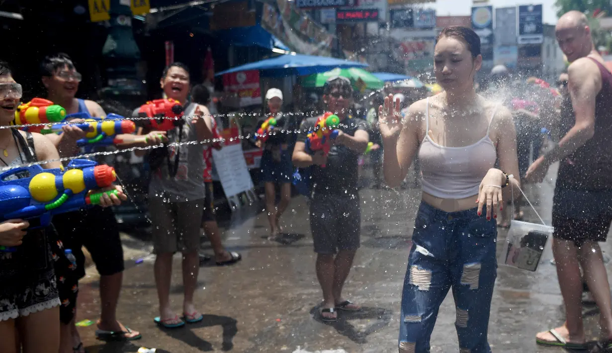 Warga menyemprotkan air ke seorang wanita saat merayakan Festival Songkran atau Tahun Baru Thailand di Bangkok, Thailand, 13 April 2019. Warga Thailand mengisi Festival Songkran dengan bersenang-senang, salah satunya perang air. (Lillian SUWANRUMPHA/AFP)
