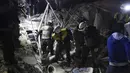 Relawan White Helmets menyingkirkan reruntuhan bangunan untuk mencari korban serangan militer di Provinsi Idlib, Suriah, Minggu, (7/1). Selain menewaskan 25 orang, serangan ini juga melukai 100 lainnya. (Syrian Civil Defense White Helmets via AP)