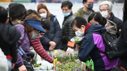 Pengunjung membeli tanaman dan bunga pada hari pembukaan pasar bunga di Hong Kong (16/1/2023). Menjelang Tahun Baru Imlek yang menandai tahun Kelinci pasar bunga di Hong Kong mulai ramai di kunjungi pengunjung. (AFP/Peter Parks)