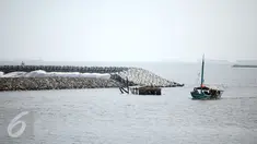 Sebuah kapal nelayan melintas diatas bebatuan tanggul pemecah ombak di Pantai Ancol, Jakarta, Minggu (24/4/2016). Tanggul ini diperuntukan mencegah banjir rob yang sudah sering menimpa daerah Jakarta Utara dan sekitarnya.(Liputan6.com/Faizal Fanani)