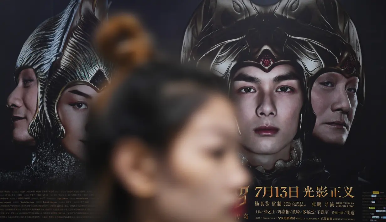 Seorang wanita berjalan melewati poster film Asura di stasiun kereta bawah tanah di Beijing, Selasa (17/7). Tim produser secara tiba-tiba menarik kembali Asura, film termahal di China yang baru tayang sepekan di bioskop. (AFP/GREG BAKER)