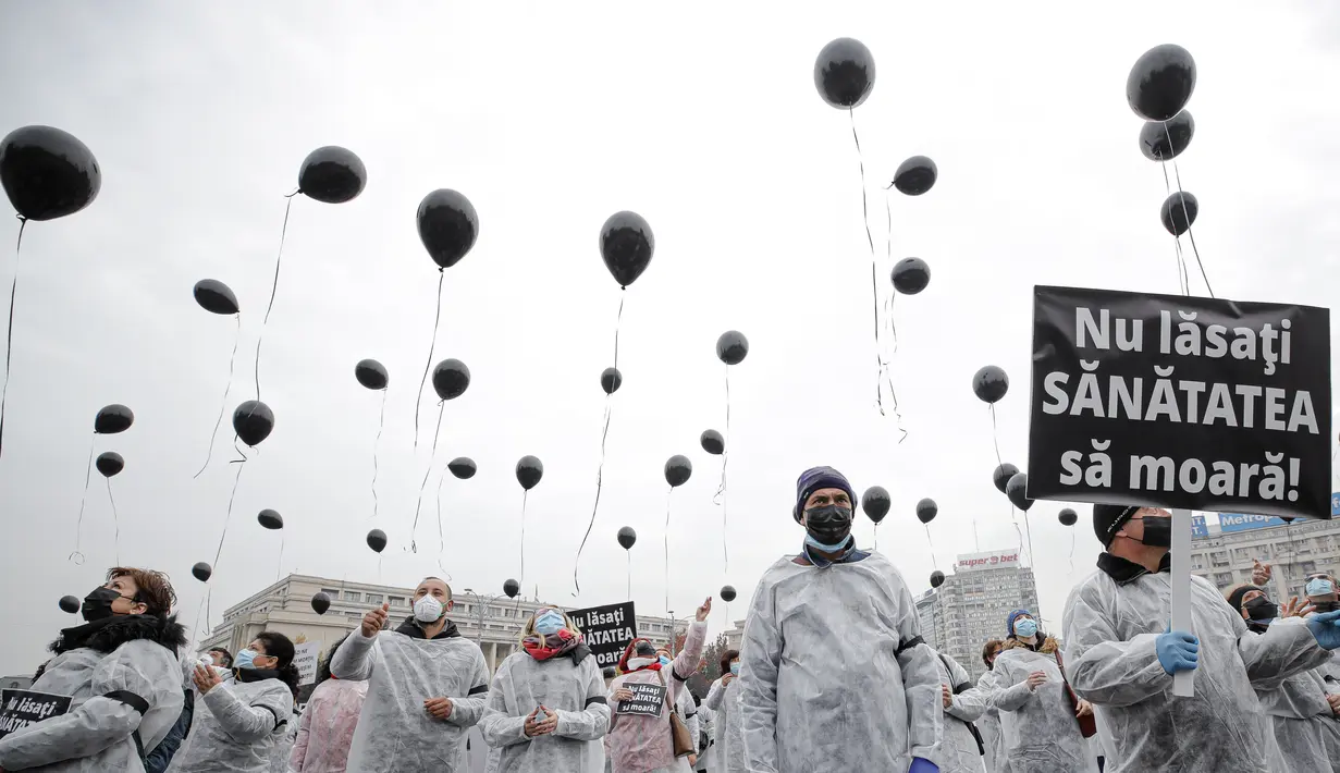 Para petugas medis yang mengenakan masker memegang balon hitam di Bucharest, Rumania, Selasa (17/11/2020). Aksi tersebut untuk mengenang pasien COVID-19 yang tewas dalam kebakaran di instalasi gawat darurat rumah sakit di Piatra Neamt, Rumania pada 14 November 2020 lalu.  (AP Photo/Vadim Ghirda)