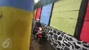 Pengendara melintas dekat tembok warna-warni di Kampung Penas Tanggul, Cipinang Besar Selatan, Jakarta, Kamis (23/3). Kampung warna-warni tanpa rokok itu dibuat warga sebagai upaya perlindungan bagi perempuan dan anak. (Liputan6.com/Immanuel Antonius)