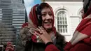 Seorang wanita tersenyum saat menggunakan kerudung bermotif bendera AS selama perayaan Hari Hijab Sedunia di depan Balai Kota, New York, Rabu (1/2). (Spencer Platt / Getty Images / AFP)