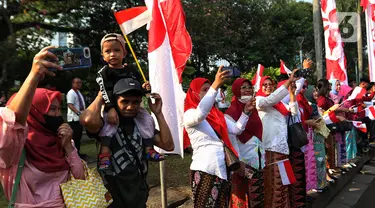 Masyarakat menyaksikan proses kirab budaya di sepanjang area Monumen Nasional (Monas) di Jakarta, Kamis (17/8/2023). Pasukan kirab sendiri diikuti peserta dari beragam elemen masyarakat, mulai pelajar hingga ibu-ibu berkebaya. (Liputan6.com/Angga Yuniar)