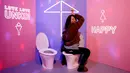 Seorang pengunjung berpose di toilet pajangan yang dipamerkan di Museum Unko di Yokohama, Jepang pada Rabu (17/4). Unko Museum Unko merupakan museum interaktif yang mengubah kotoran menjadi sesuatu yang lebih rapi dan bahkan lucu. (REUTERS/Kim Kyung-hoon)