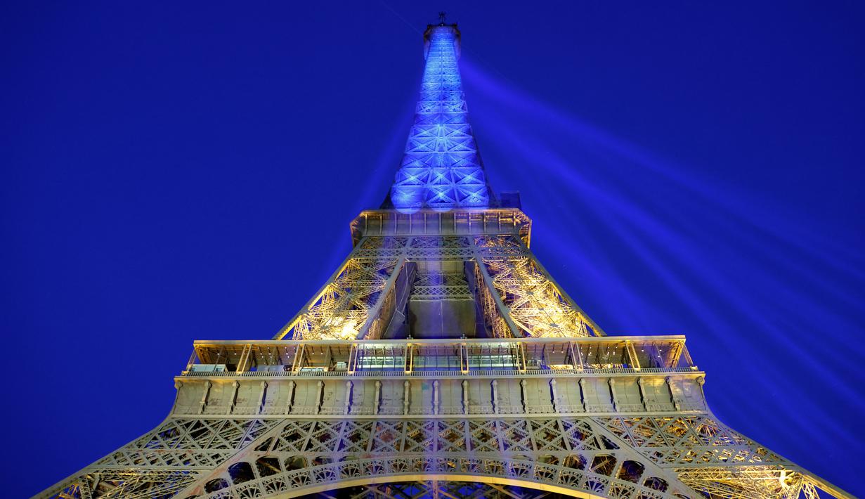 <p>Sebuah foto menunjukkan Menara Eiffel di Paris diterangi dengan warna bendera nasional Ukraina, pada 9 Mei 2022. Memperingati Hari Eropa, Menara Eiffel memproyeksikan bendera Ukraina sebagai solidaritas untuk rakyat Ukraina di tengah invasi Rusia. (Ludovic MARIN / AFP)</p>