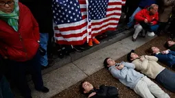 Pengunjuk rasa yang didominasi para siswa SMA berbaring di jalan depan Gedung Putih, Washington, Senin (19/2). Mereka berbaring selama tiga menit tanpa peduli kedinginan atau kebasahan. (AP Photo/Evan Vucci)