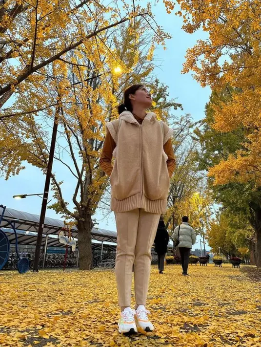 Berpose dengan latar belakang pohon berguguran, Syahnaz tampil chic mengenakan sweater kuning dipadukan dengan vest warna coklat susu. @syahnazs.