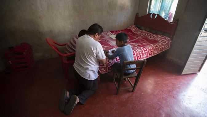 Agustin Vazquez membantu putra-putranya Samuel dan Hector mengerjakan tugas sekolah di tengah pandemi COVID-19 di rumah mereka, Nuevo Yibeljoj, Chiapas, Meksiko, 11 September 2020. (AP Photo/Eduardo Verdugo)