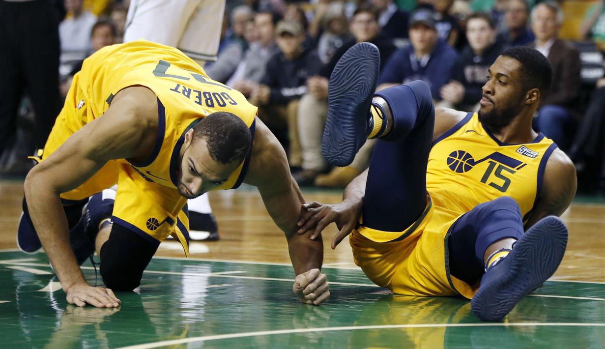 Dua pemain Utah Jazz, Rudy Gobert (kiri) dan Derrick Favors (15) jatuh saat berebut bola dengan pemain Boston Celtics pada lanjutan NBA basketball game di TD Garden, Boston, (15/12/2017). Utah Jazz menang 107-95. (AP/Michael Dwyer)