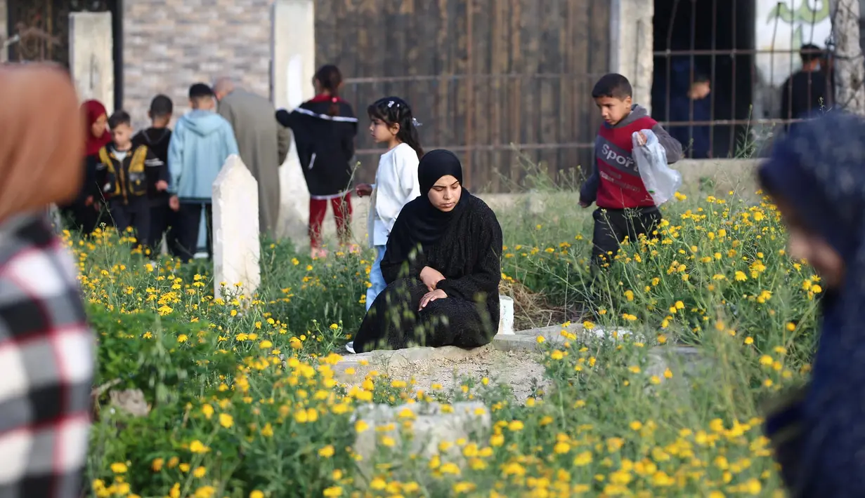 Warga Palestina mengunjungi makam kerabatnya usai melaksanakan salat Idul Fitri 1446 Hijriah di kamp Nuseirat, Jalur Gaza tengah pada 30 Maret 2025. (Eyad BABA/AFP)