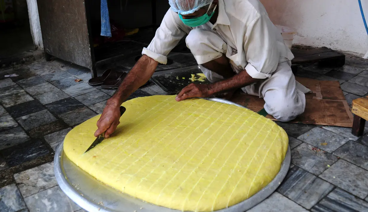 Seorang pria membuat penganan manis tradisional di hari raya Idul Fitri di Peshawar, Pakistan barat laut, pada 25 Mei 2020. Warga Pakistan memiliki tradisi memakan penganan manis saat merayakan Idul Fitri, yang menandai akhir bulan puasa Ramadan. (Xinhua/Saeed Ahmad)