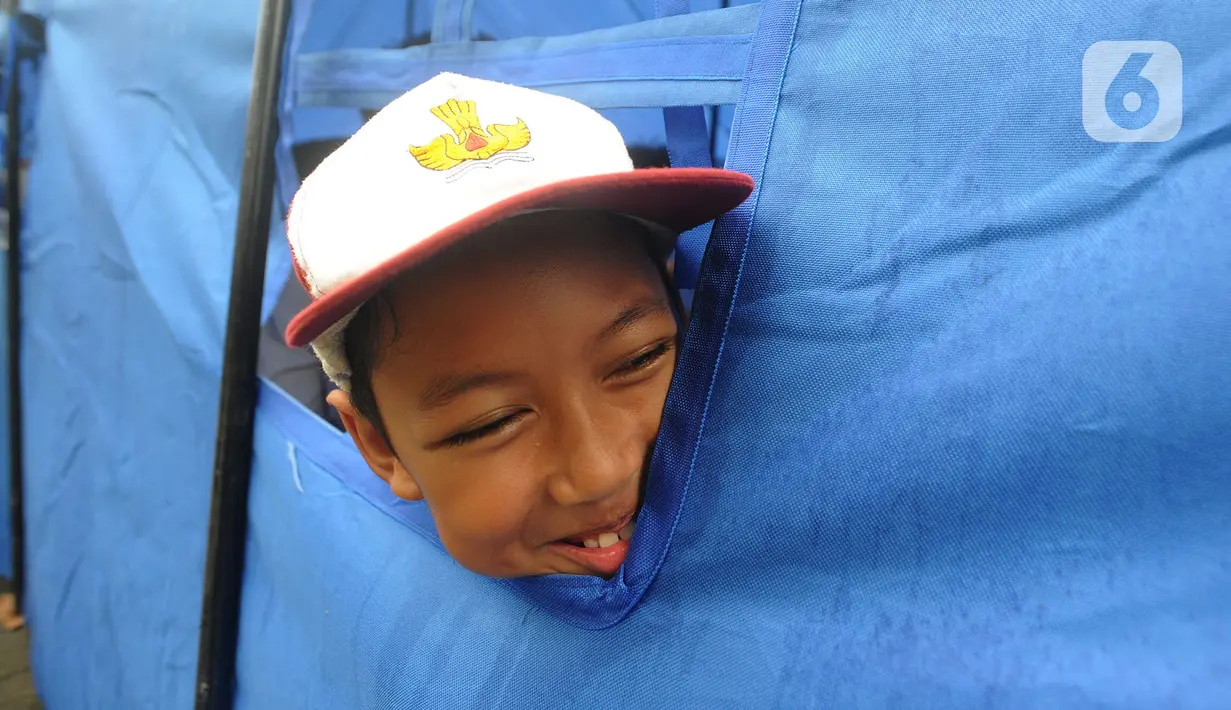 Seorang murid mengintip di jendela tenda darurat saat mengikuti kegiatan belajar di SDN Cirimekar 2, Cibinong, Bogor, Senin (6/1/2020). Tenda darurat dibuat akibat bangunan atau kelas roboh saat hujan deras  pada hari Rabu (1/1/2020) lalu. (merdeka.com/Arie Basuki)
