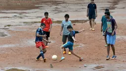Anak-anak sekolah India bermain bola dekat genangan air di Bangalore, India, Rabu (11/11/2015) WIB.  (AFP Photo/Manjunath Kiran)