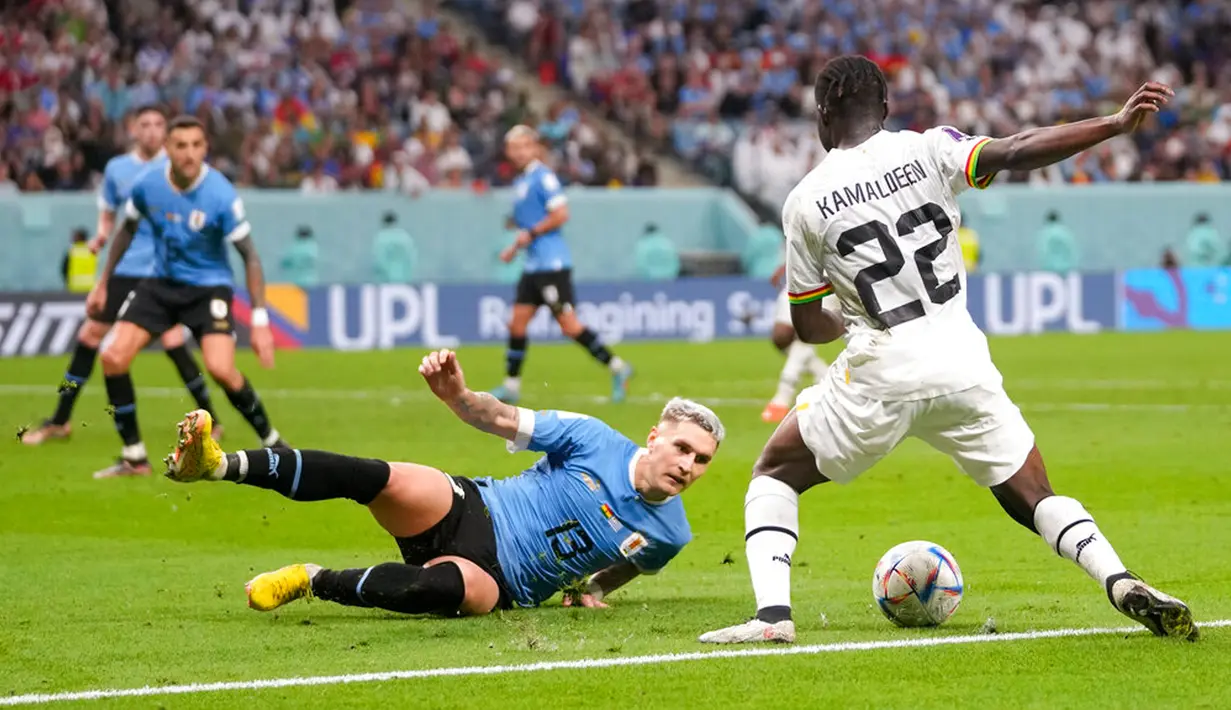 Pemain Uruguay Guillermo Varela mencoba menghalau pemain Ghana Kamaldeen Sulemana pada pertandingan sepak bola Grup H Piala Dunia 2022 di Stadion Al Janoub, Al Wakrah, Qatar, 2 Desember 2022. Uruguay mengalahkan Ghana 2-0, namun tetap tak lolos ke babak 16 besar Piala Dunia 2022. (AP Photo/Darko Vojinovic)