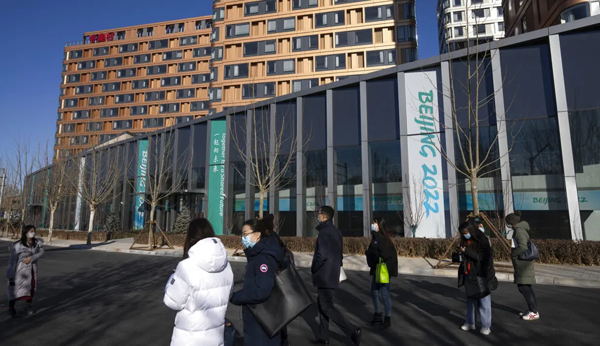 Pengunjung berjalan melewati gedung-gedung di Desa Olimpiade Musim Dingin, Beijing, China, Jumat, 24 Desember 2021. Olimpiade dan Paralimpiade Musim Dingin 2022 akan diadakan mulai bulan Februari. (AP Photo/Mark Schiefelbein)