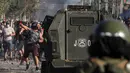 Demonstran melempar batu saat saat bentrok dengan polisi di tengah pandemi virus corona Covid-19 selama penguncian wilayah (lockdown) di lingkungan miskin di Santiago, Chili, (18/5/2020). (AP Photo/Esteban Felix)
