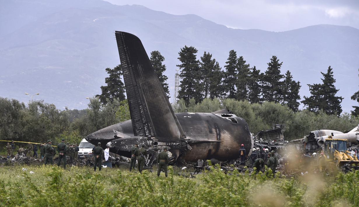 Petugas keamanan dan tim penyelamat berjaga di sekitar reruntuhan pesawat tentara Aljazair yang jatuh di dekat pangkalan udara Boufarik, Aljazair (11/4). Insiden ini menewaskan 257 orang yang berada di dalam pesawat tersebut. (AFP Photo/Ryad Krmadi)