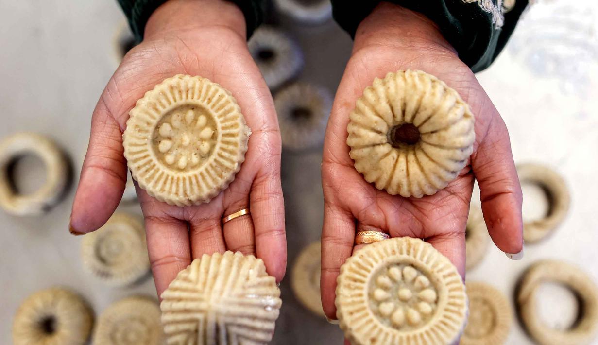 Bagi warga Palestina, roti ini sangat populer yang menjadi penanda akhir Ramadan dan untuk disajikan saat perayaan Hari Raya Idul Fitri. Tampak dalam foto, seorang wanita memegang biskuit tradisional "kaak" yang baru saja dibuat menjelang Idul Fitri, hari raya yang menandai berakhirnya bulan puasa suci Ramadhan bagi umat Muslim, di Kota Gaza pada 16 Maret 2026. (Omar AL-QATTAA/AFP)