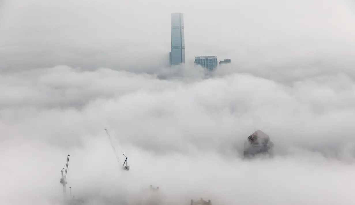 Bangunan tempat tinggal yang diselimuti kabut dan Pusat Perdagangan Internasional (ICC di atas) di Hong Kong, Selasa (22/3/2022). Kabut tebal menyelimuti Hong Kong pada musim semi ketika wilayah tersebut dipengaruhi oleh udara dingin dan hangat bergantian. (AFP/Dale De La Rey)
