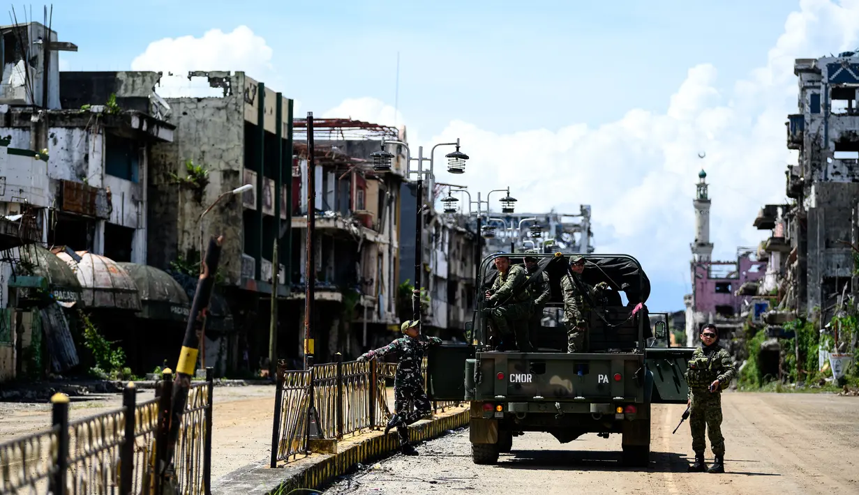 Tentara berpatroli di antara gedung-gedung yang hancur di Kota Marawi, Provinsi Lanao del Sur, Filipina, Kamis (23/5/2019). Setengah wilayah dari kota yang pernah menjadi salah satu tempat terindah di Filipina itu kini hanya beton dan kerangka bangunan akibat serangan udara. (Noel CELIS/AFP)