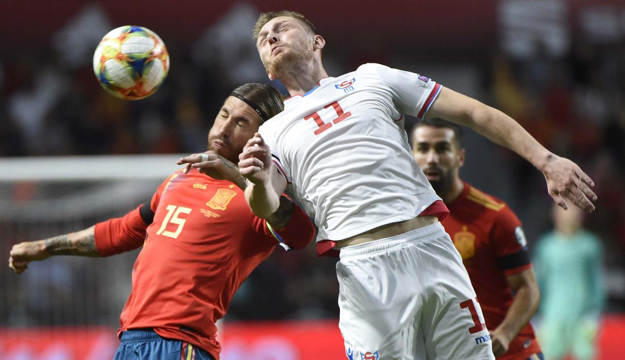 Bek Spanyol, Sergio Ramos, duel udara dengan striker Kepulauan Faroe, Klaemint Olsen, pada laga Kualifikasi Piala Eropa 2020 di Stadion El Molinon, Gijon, Minggu (8/9). Spanyol menang 4-0 atas Kepulauan Faroe. (AFP/Miguel Riopa)