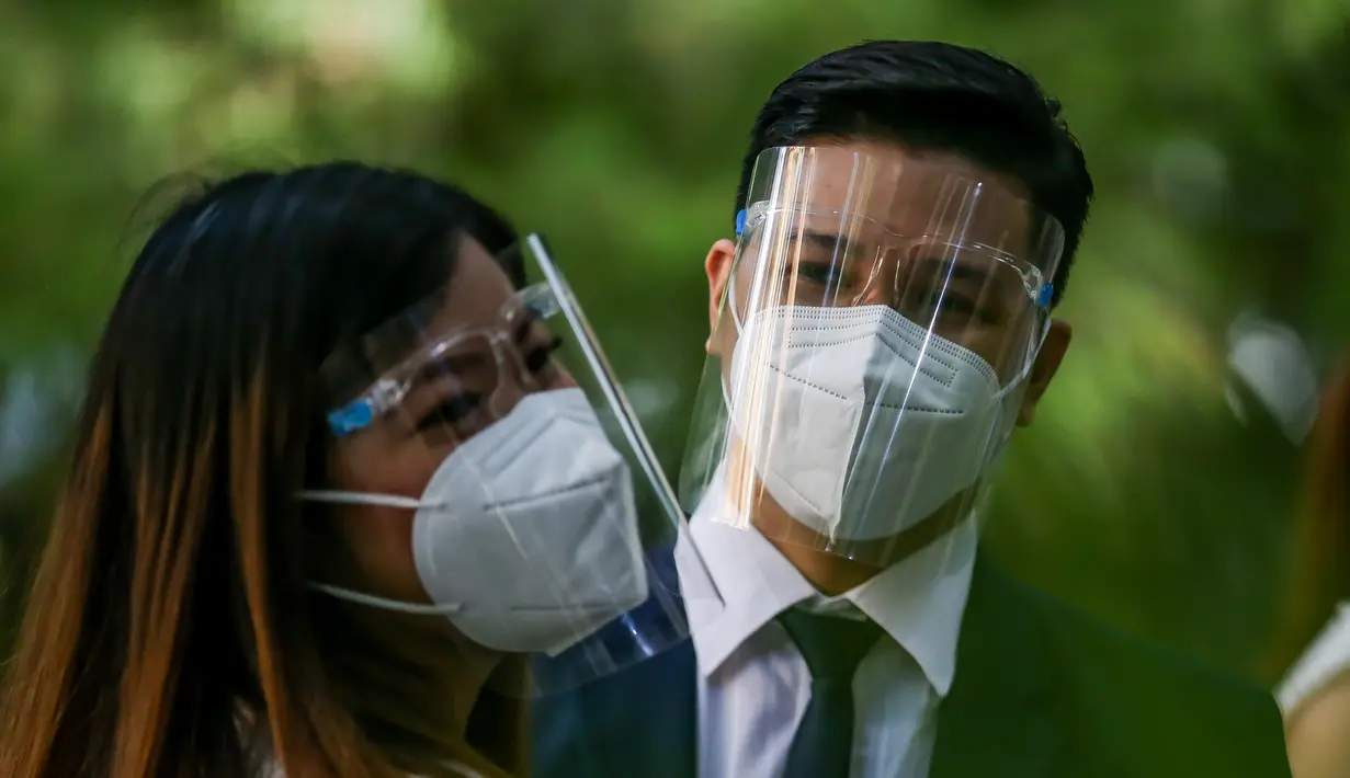 Pasangan mengenakan masker dalam "pernikahan massal bermasker" di sebuah taman di Filipina (15/12/2020). Pemerintah Filipina telah memberlakukan kebijakan untuk penggunaan masker di tengah kekhawatiran lonjakan kasus COVID-19 selama musim liburan. (Xinhua/Rouelle Umali)