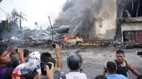 Sejumlah warga berkumpul di lokasi jatuhnya pesawat Hercules C-130 yang jatuh di kawasan perumahan, Medan, Selasa (30/6/2015). Hercules C-130 milik TNI AU jatuh tidak lama setelah lepas landas. (AFP PHOTO/Muhammad Zulfan Dalimunthe)
