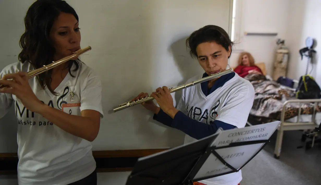 Dua orang relawan dari Musica Para el Alma memainkan alat musiknya di Rumah Sakit Alvarez di Buenos Aires, Argentina (12/6). Mereka juga sering tampil di sekolah pendidikan khusus, panti jompo dan institusi publik lainnya. (AFP Photo/Eitan Abramovich)