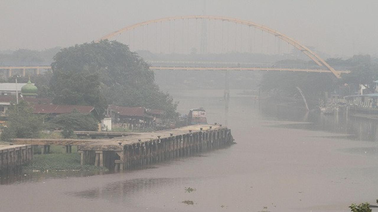Kabut asap pekat menyelimuti rumah dan Jembatan Siak III di Pekanbaru mulai terlihat samar.