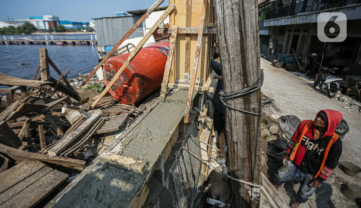 Pekerja menyelesaikan proyek peninggian tanggul di kawasan Muara Baru, Jakarta, Jumat (6/10/2023). (Liputan6.com/Faizal Fanani)