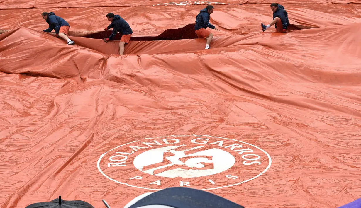 Para petugas menutup lapangan Roland Garros saat turun hujan pada turnamen Prancis Terbuka 2016 di Roland Garros, (28/5/2016). (AFP/Miguel Medina)