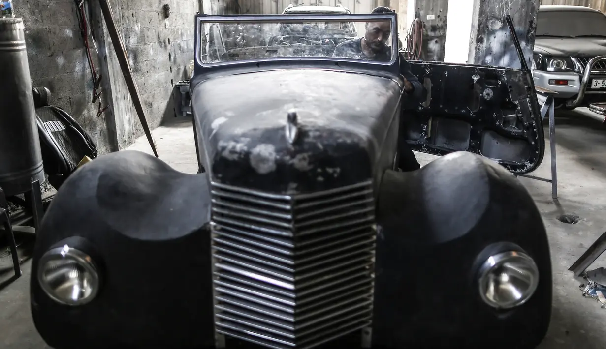 Munir Shindy saat merestorasi mobil tua di bengkelnya di Kota Gaza (28/10/2019). Pria 40 tahun ini sudah bekerja merestorasi mobil selama 12 tahun. Mobil terakhir yang dikerjakan Shindi adalah Armstrong Siddeley Hurricane 1946. (AFP Photo/Mahmud Hams)