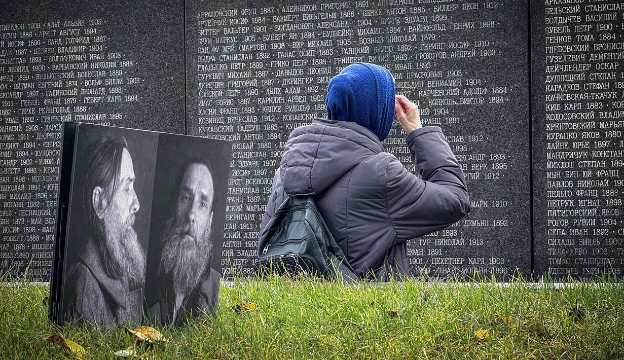 Seorang perempuan mengunjungi tugu peringatan bagi para korban represi politik di Butovo, di luar Moskow, pada Kamis 30 Oktober 2025, menandai hari peringatan. Pada tahun 1995, Gereja Ortodoks Rusia mengambil alih kepemilikan Butovo dan mendirikan kompleks peringatan, termasuk tembok peringatan yang memuat nama-nama korban yang teridentifikasi. (Nikita BORISSOV/AFP)