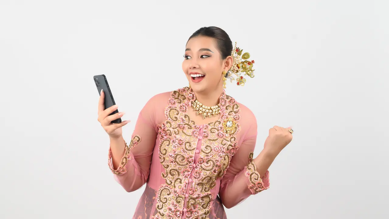 Seorang perempuan mengenakan kebaya sambil memegang HP (Foto Dok: Freepik/johnstocker)