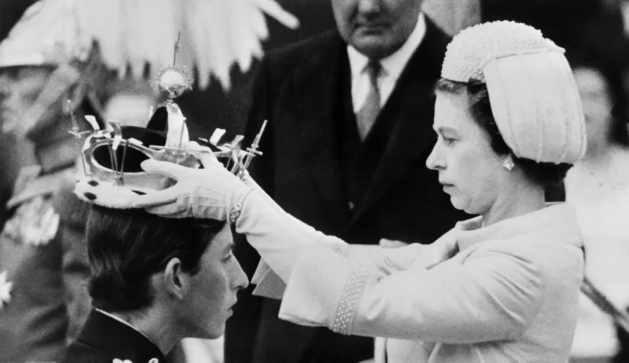 Dalam file foto ini diambil pada 01 Juli 1969 Ratu Elizabeth II meletakkan mahkota pada putranya Pangeran Charles selama penobatannya sebagai Pangeran Wales yang baru di Caernarfon. (Photo by CENTRAL PRESS / AFP)