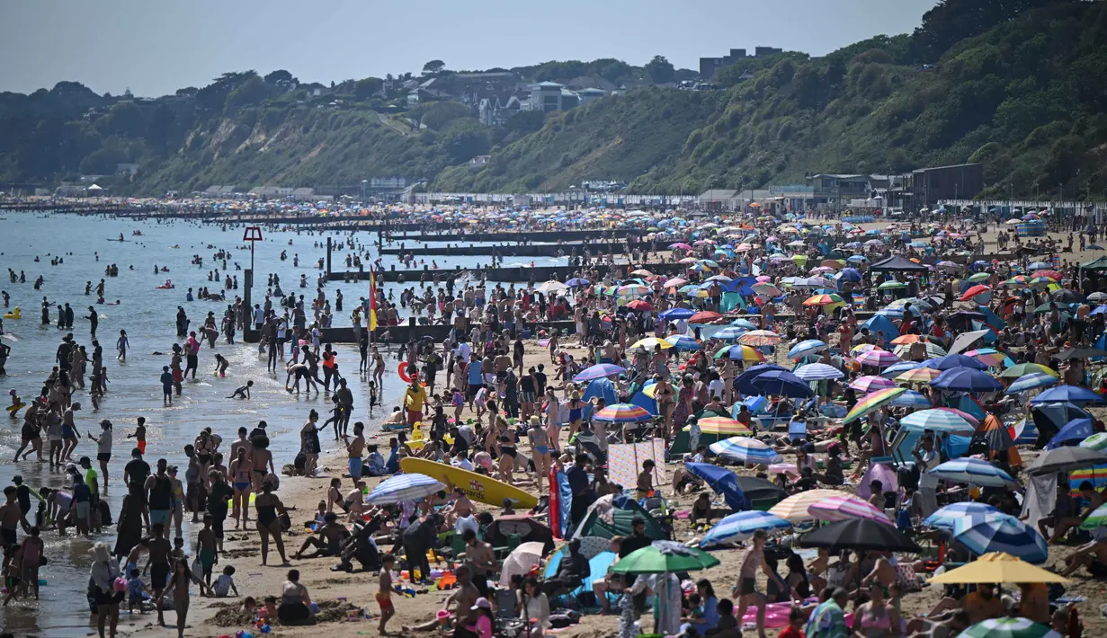 Para pengunjung berjemur menikmati sinar matahari di Pantai Bournemouth, Selatan Inggris pada Selasa 26 Mei 2026, saat kondisi gelombang panas menyebar ke sebagian wilayah tenggara Inggris dan London. (JUSTIN TALLIS/AFP)