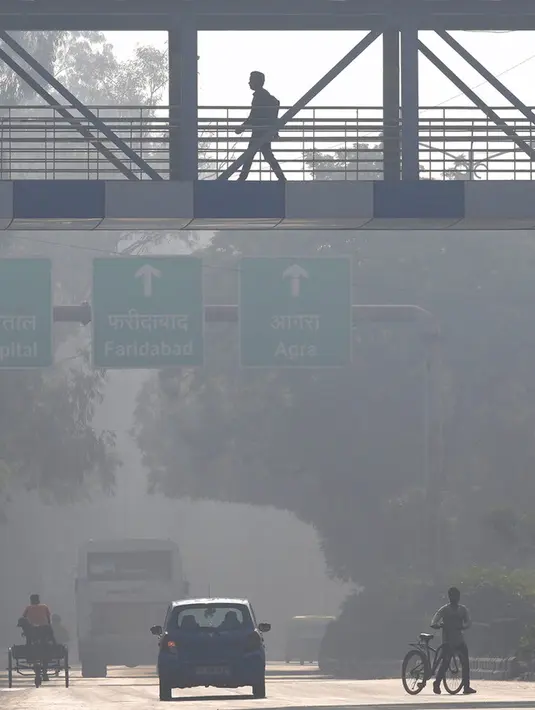 Seorang pekerja melintasi jembatan di tengah kabut pagi dan kabut asap beracun di New Delhi, India,  17 November 2021. Indeks Kualitas Udara di New Delhi mencapai 499 dari 500, meningkatkan risiko orang sehat dapat juga mengalami penyakit pernapasan. (AP Photo/Manish Swarup)