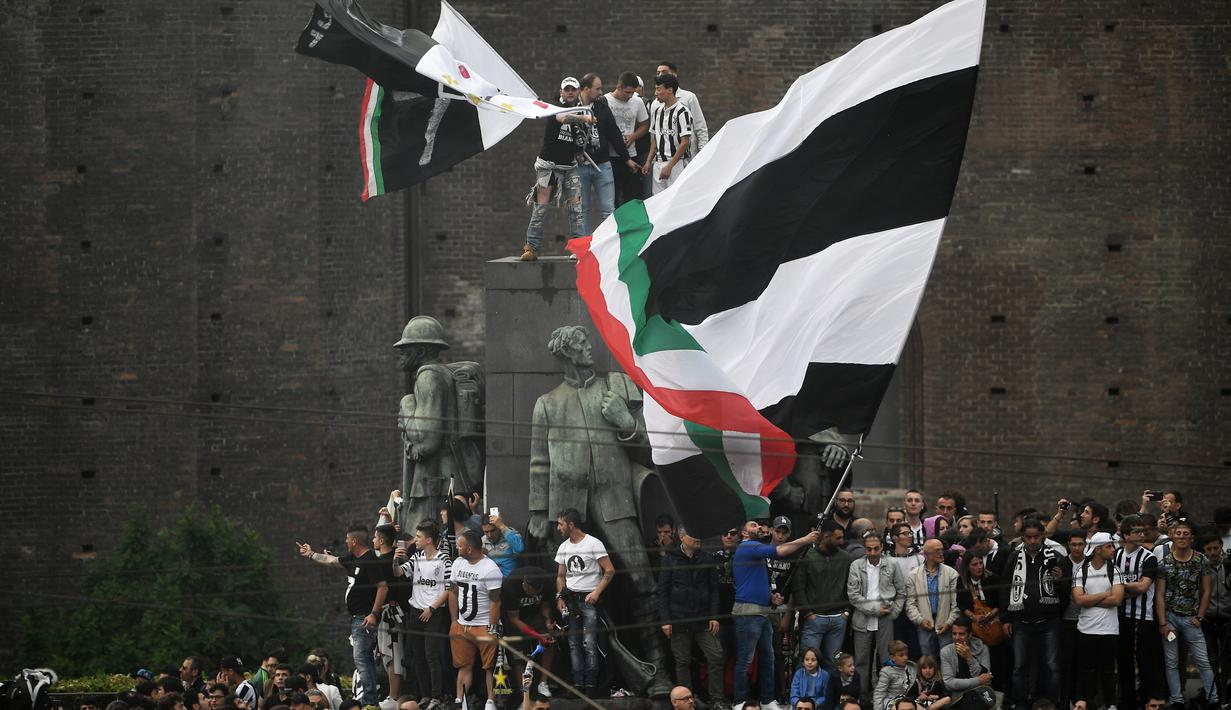 Fans Juventus memanjat monumen kota saat merayakan keberhasilan timnya meraih trofi Serie A di Turin, Italia, (19/5/2018). Juventus meraih gelar Seri A tujuh kali secara beruntun. (AFP/Marco Bertorello)